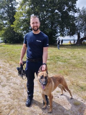 Zdjęcie przedstawiające policjanta z psem służbowym.