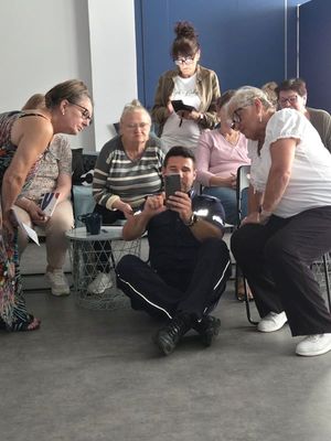 Policjant pokazujący seniorom na urządzeniu mobilnym działanie Krajowej Mapy Zagrożeń Bezpieczeństwa