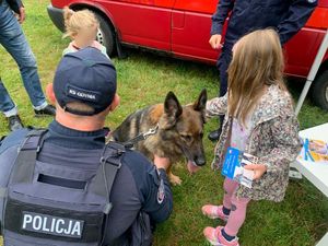 Zdjęcie przedstawiające przewodnika psa służbowego z psem oraz dwójką dzieci.