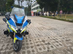 Zdjęcie przedstawiające motocykl policyjny przed szkołą. Widać również dorosłych i dzieci.