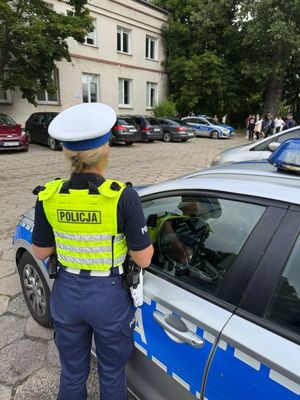Zdjęcie przedstawiające policjantkę obok radiowozu przy jednej ze szkół.