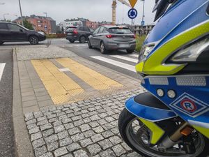 Zdjęcie przedstawiające motocykl przed rondem oraz pojazdy.