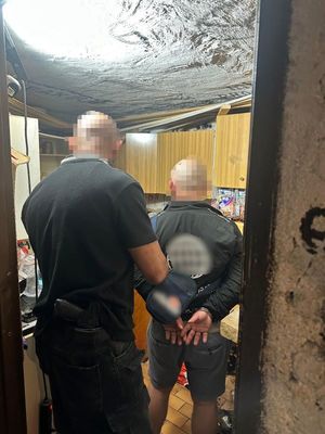 Zdjęcie przedstawia zatrzymanego mężczyznę wraz z funkcjonariuszem