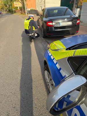 Zdjęcie przedstawiające policjanta sprawdzającego stan opon.