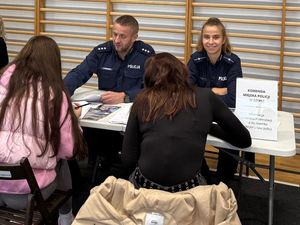 Policjanci wraz z uczestnikiem targów wypełniającym formularz zgłoszeniowy do Policji.