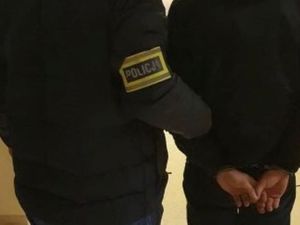 Zdjęcie poglądowe, przedstawiające sylwetkę policjanta i zatrzymanego mężczyzny.