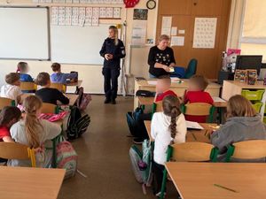 Policjanta z uczniami szkoły podstawowej na zajęciach o bezpieczeństwie