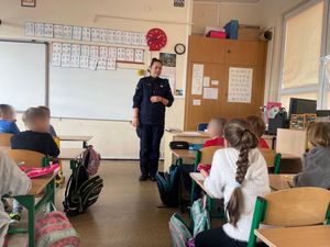 Policjanta z uczniami szkoły podstawowej na zajęciach o bezpieczeństwie