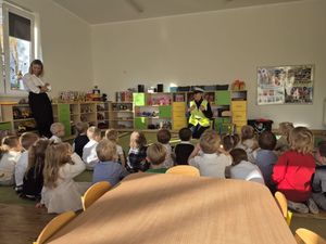 Zdjęcie przedstawia policjantkę, prowadzącą zajęcia z dziećmi.