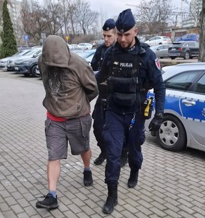 Podejrzany prowadzony przez dwóch policjantów.