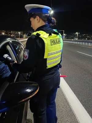 Zdjęcie poglądowe przedstawia policjantkę podczas kontroli drogowej.