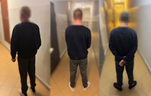 trzy zatrzymane osoby stojące tyłem