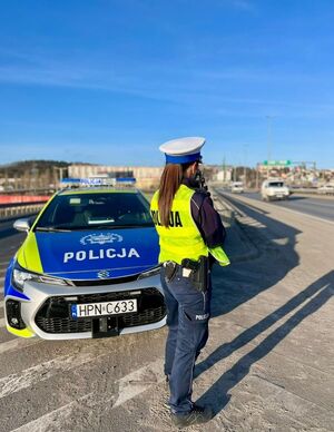 Zdjęcie przedstawia policjanta mierzącego prędkość i kontrolującego pojazd.