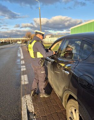 Zdjęcie przedstawia policjanta mierzącego prędkość i kontrolującego pojazd.