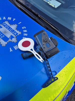 Zdjęcie przedstawia policjanta mierzącego prędkość i kontrolującego pojazd.